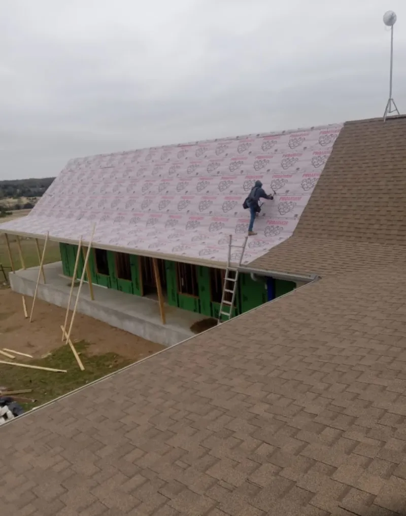 Worker preparing underlayment for a metal roof installation in Mount Horeb